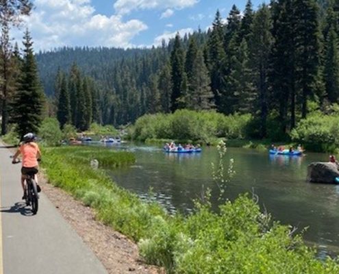 People cycling and floating on a river spending time outdoors after buying Nevada new homes.