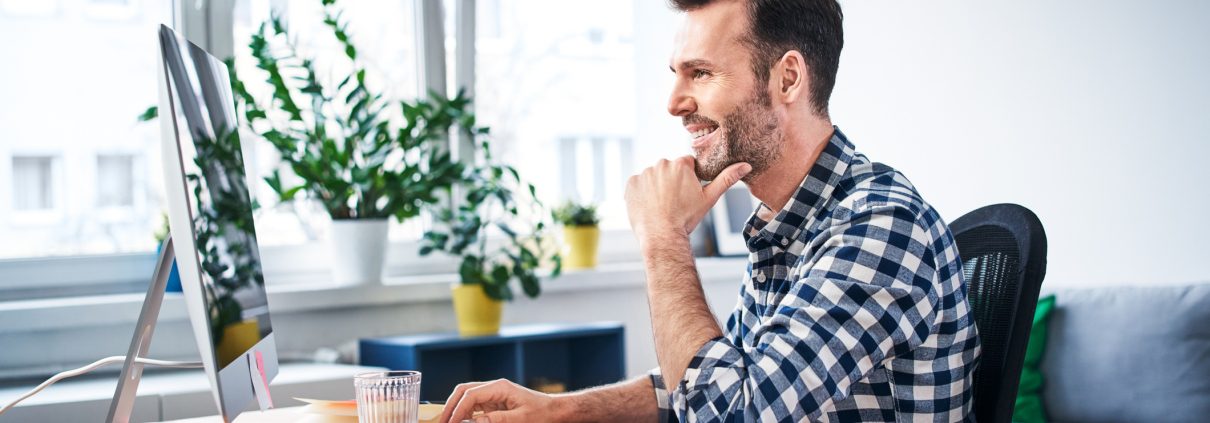 A man sitting in front of his computer in a home office he created.